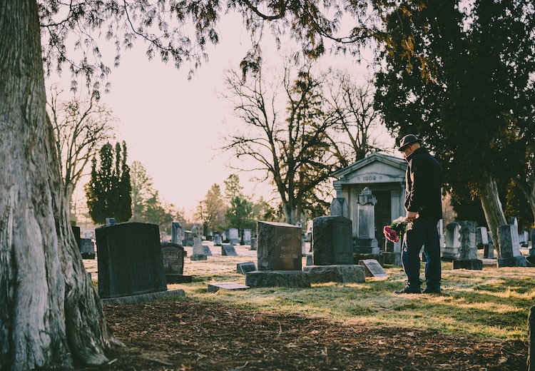 man-standing-at-grave-with-flowers